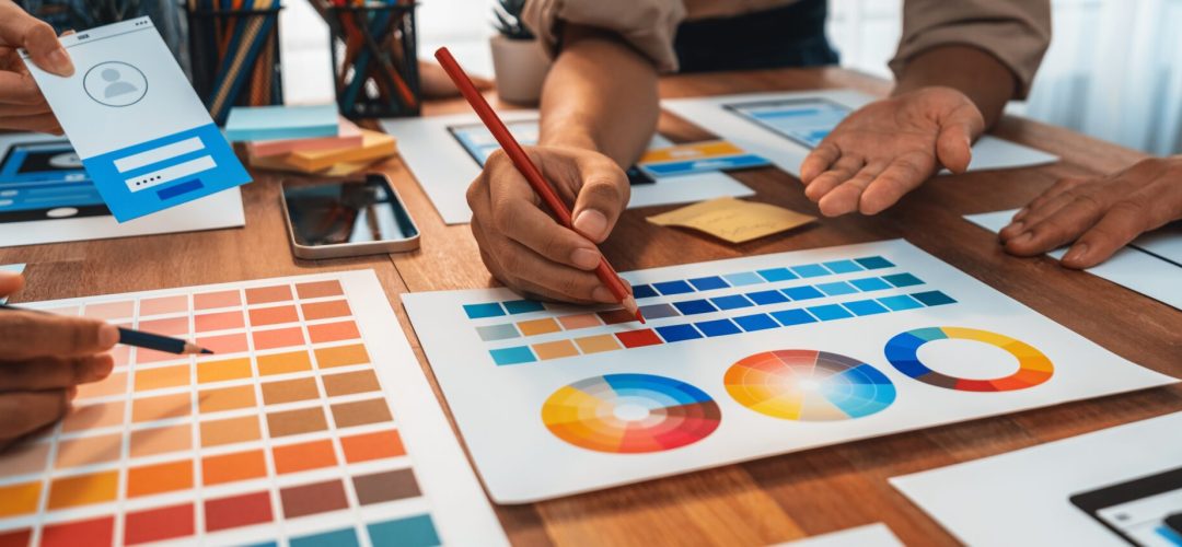 Panorama shot of front-end developer team brainstorming UI and UX designs for mobile app on paper wireframe interface. User interface development team planning for user-friendly UI design. Scrutinize