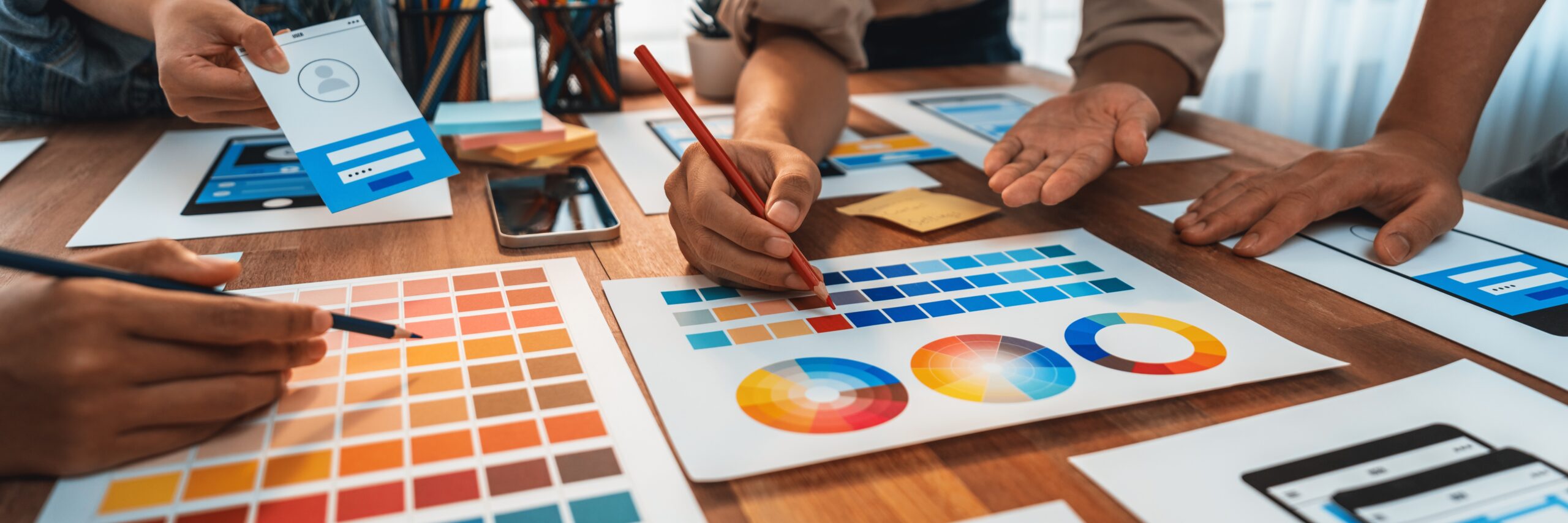 Panorama shot of front-end developer team brainstorming UI and UX designs for mobile app on paper wireframe interface. User interface development team planning for user-friendly UI design. Scrutinize